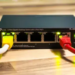 Przełącznik sieciowy TP-Link z 4 portami PoE+ i zasilaniem poe. Podłączone kable sieciowe.