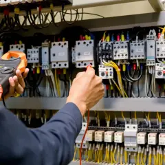 Ręce elektryka z multimetrem przy panelu sterowania. Przygotowanie do egzaminu SEP: pytania i odpowiedzi.