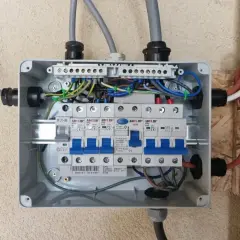 Rozdzielnica elektryczna z bezpiecznikami. Widać przewody zasilające i instalacyjne. Zastanawiasz się nad zasilanie bezpiecznika z góry czy z dołu?