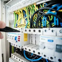 Ręka majstruje przy skrzynce z bezpiecznikami. Zastanawiasz się, ile zarabia elektryk w Niemczech?