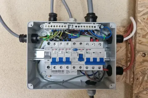 Rozdzielnica elektryczna z bezpiecznikami. Widać przewody zasilające i instalacyjne. Zastanawiasz się nad zasilanie bezpiecznika z góry czy z dołu?