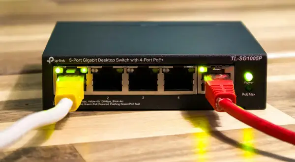 Przełącznik sieciowy TP-Link z 4 portami PoE+ i zasilaniem poe. Podłączone kable sieciowe.