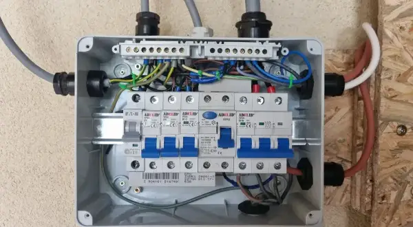Rozdzielnica elektryczna z bezpiecznikami. Widać przewody zasilające i instalacyjne. Zastanawiasz się nad zasilanie bezpiecznika z góry czy z dołu?