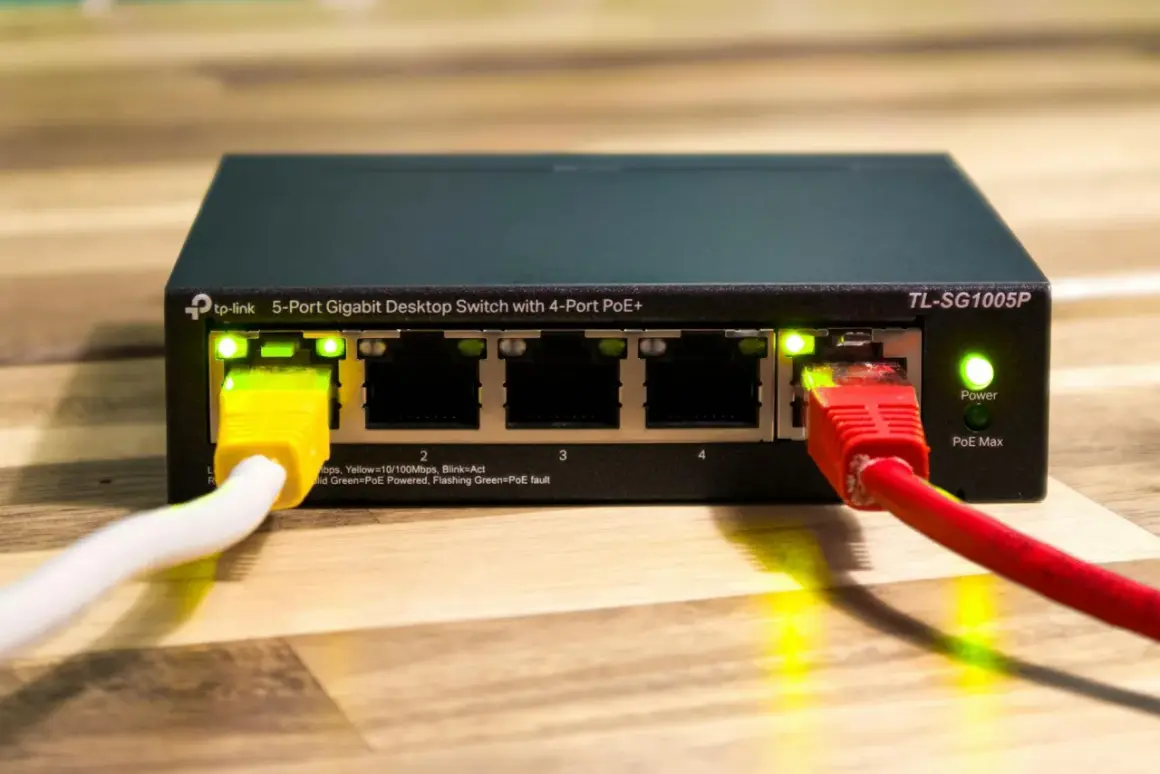 Przełącznik sieciowy TP-Link z 4 portami PoE+ i zasilaniem poe. Podłączone kable sieciowe.