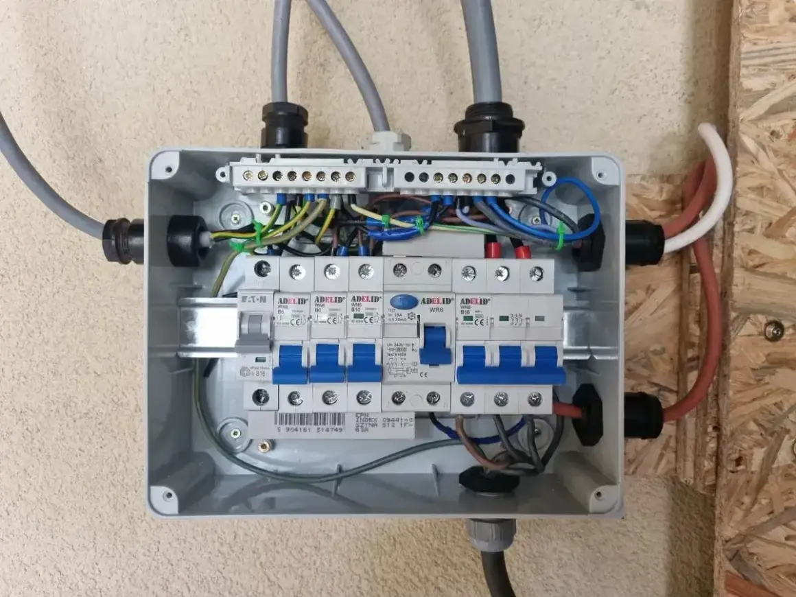 Rozdzielnica elektryczna z bezpiecznikami. Widać przewody zasilające i instalacyjne. Zastanawiasz się nad zasilanie bezpiecznika z góry czy z dołu?