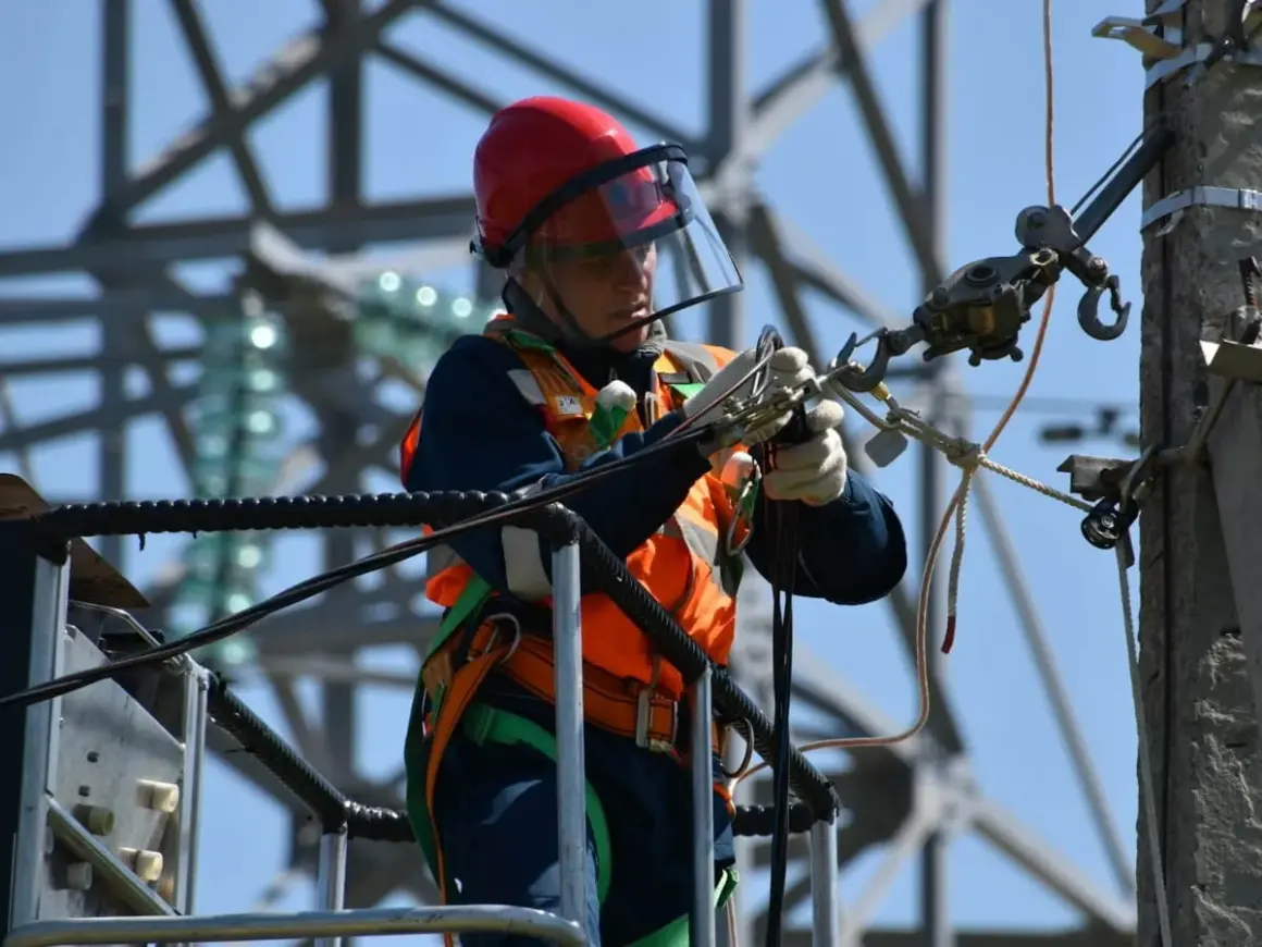 Elektryk w kasku i kamizelce pracujący na wysokości. Ciekawe, ile zarabia elektryk za taką odpowiedzialną pracę.