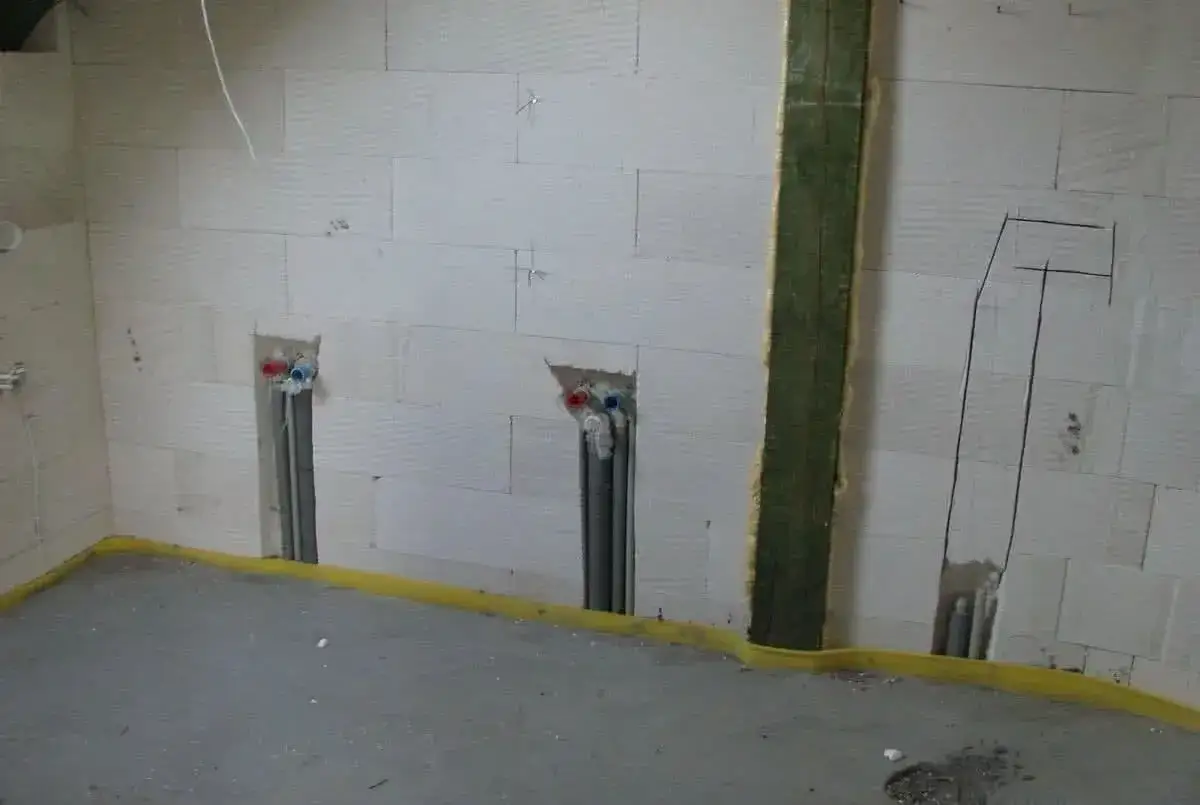 Ściana z bloczków z wyciętymi otworami na instalację wodną i elektryczną. Bruzdowanie pod kable cena jest tu kluczowa dla planowania prac.