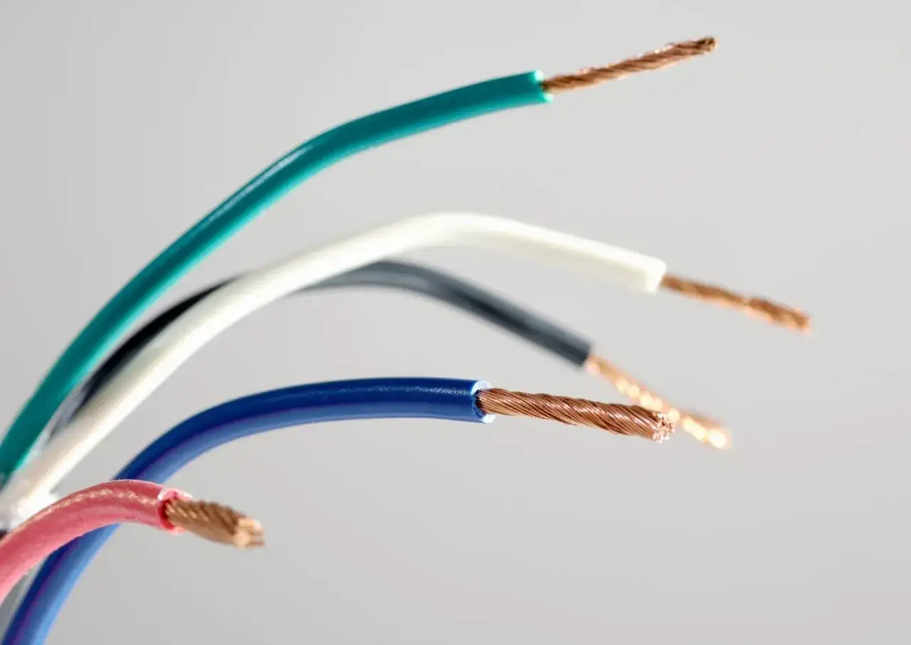 Kilka kolorowych kabli elektrycznych: zielony, biały, czarny, niebieski i różowy, z odsłoniętymi miedzianymi żyłami.