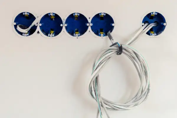 Instalacja elektryczna w trakcie. Widoczne puszki podtynkowe i przygotowane do podłączenia kable. Dowiedz się, jak podłączyć kabel 3 żyłowy do wtyczki.