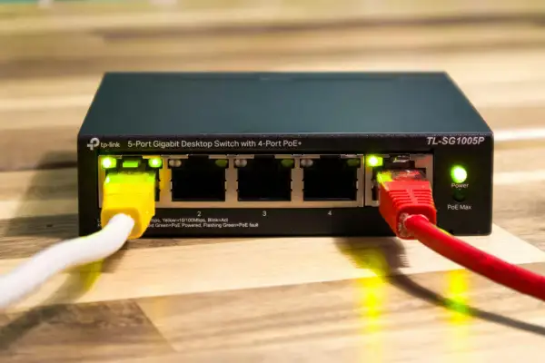 Przełącznik sieciowy TP-Link z 4 portami PoE+ i zasilaniem poe. Podłączone kable sieciowe.