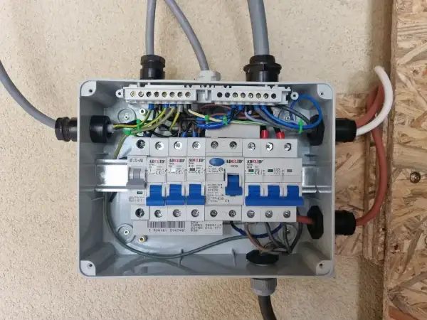 Rozdzielnica elektryczna z bezpiecznikami. Widać przewody zasilające i instalacyjne. Zastanawiasz się nad zasilanie bezpiecznika z góry czy z dołu?