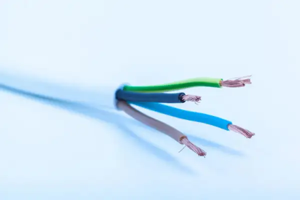 Cztery żyły kabla elektrycznego: zielona, czarna, niebieska i brązowa, gotowe do podłączenia oświetlenia.